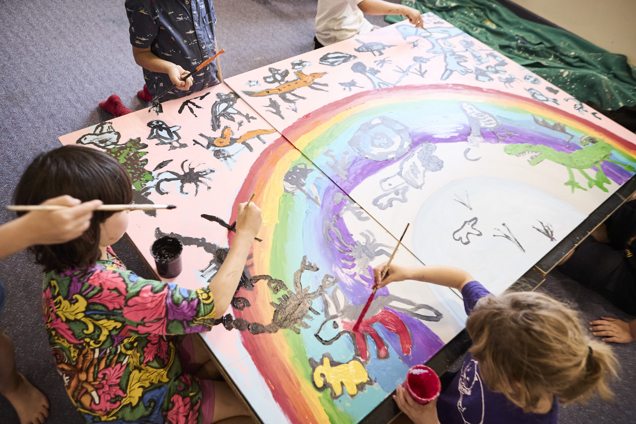 Students painting a large rainbow mural together at Daylesford Dharma School