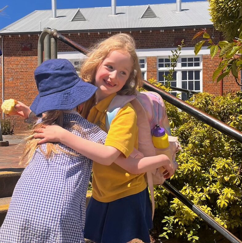 Two students hugging on the steps at Daylesford Primary School